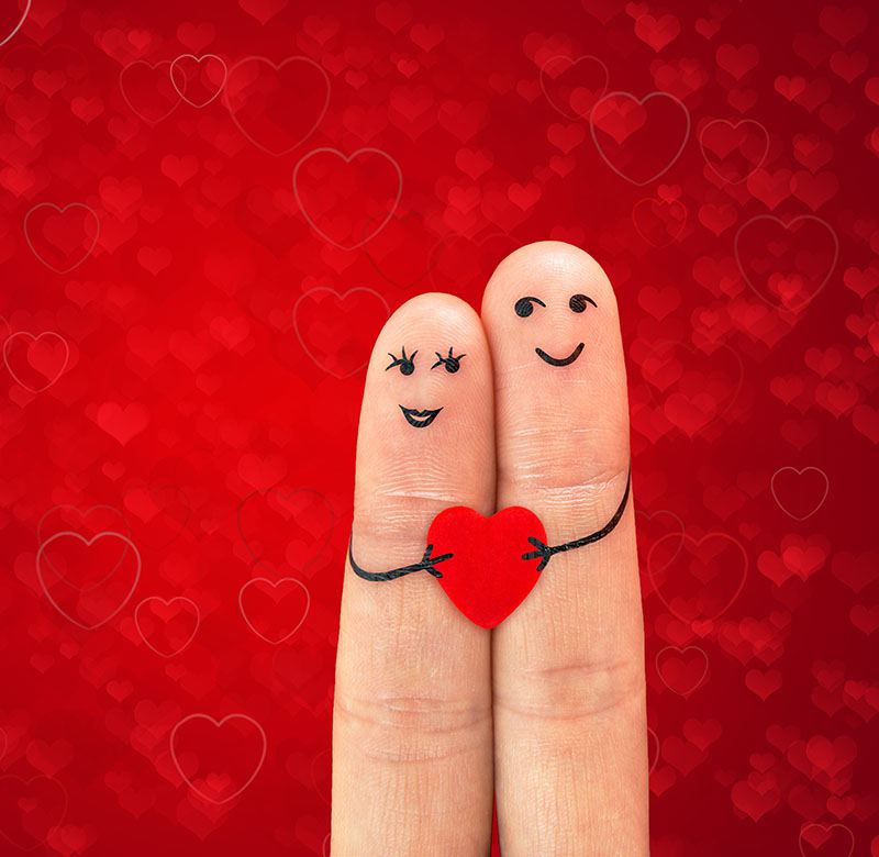 Happy couple in love with painted smiley holding red heart Happy couple in love with painted smiley holding red heart